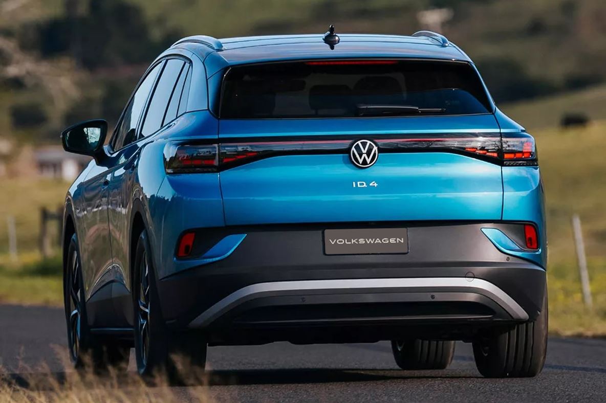 Traseira do Volkswagen ID.4 azul em estrada, com destaque para lanternas interligadas, logotipo VW e identidade visual do SUV elétrico.