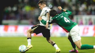 Bernard conduz a bola enquanto é agarrado por um defensor do Palmeiras durante partida pelo Brasileirão.