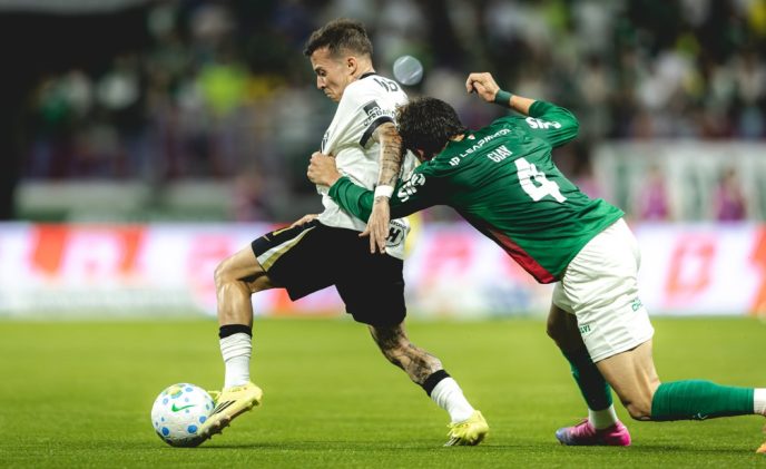 Bernard conduz a bola enquanto é agarrado por um defensor do Palmeiras durante partida pelo Brasileirão.