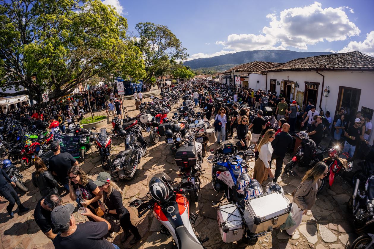 Vista ampla de rua histórica de Tiradentes tomada por motocicletas e visitantes durante o Bike Fest, com casarões coloniais, árvores e a Serra de São José ao fundo.