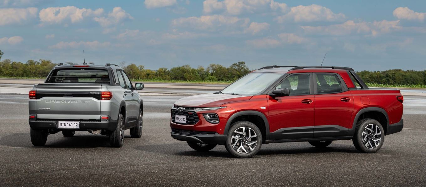 Duas Chevrolet Montana 2027 em pista, uma cinza vista pela traseira e outra vermelha em perfil lateral, destacando design externo, caçamba e visual de SUV.