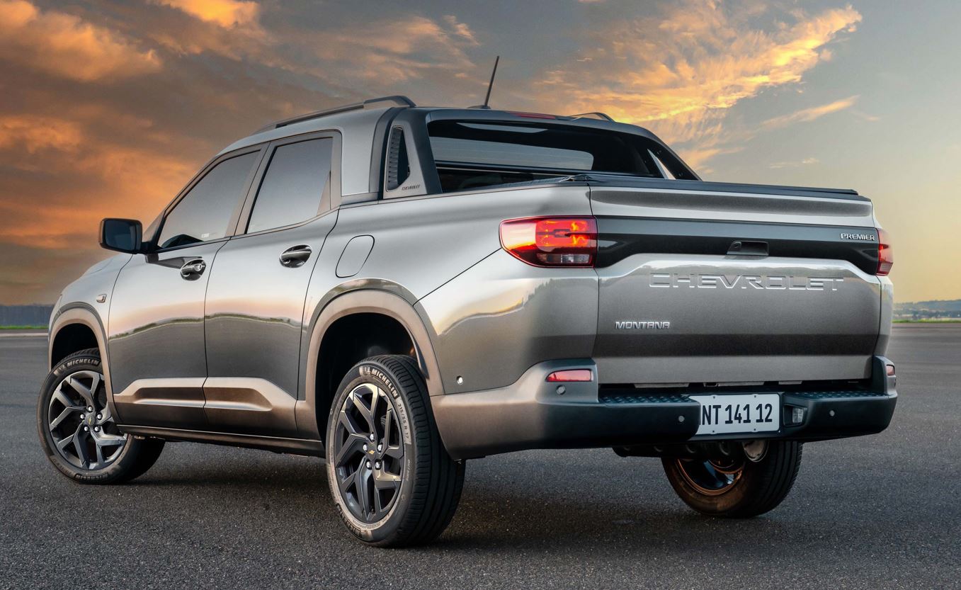 Chevrolet Montana 2027 cinza vista pela traseira, com tampa da caçamba em baixo-relevo, lanternas acesas, rodas de liga leve e Santo Antônio integrado.