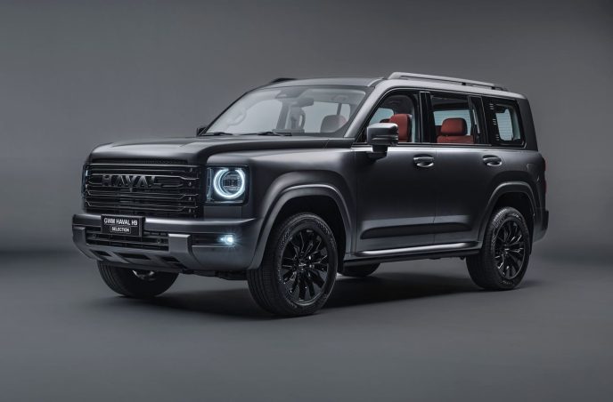 Haval H9 Selection cinza fotografado de frente e de lado, com grade preta, faróis de LED, rodas aro 19 e interior marrom.