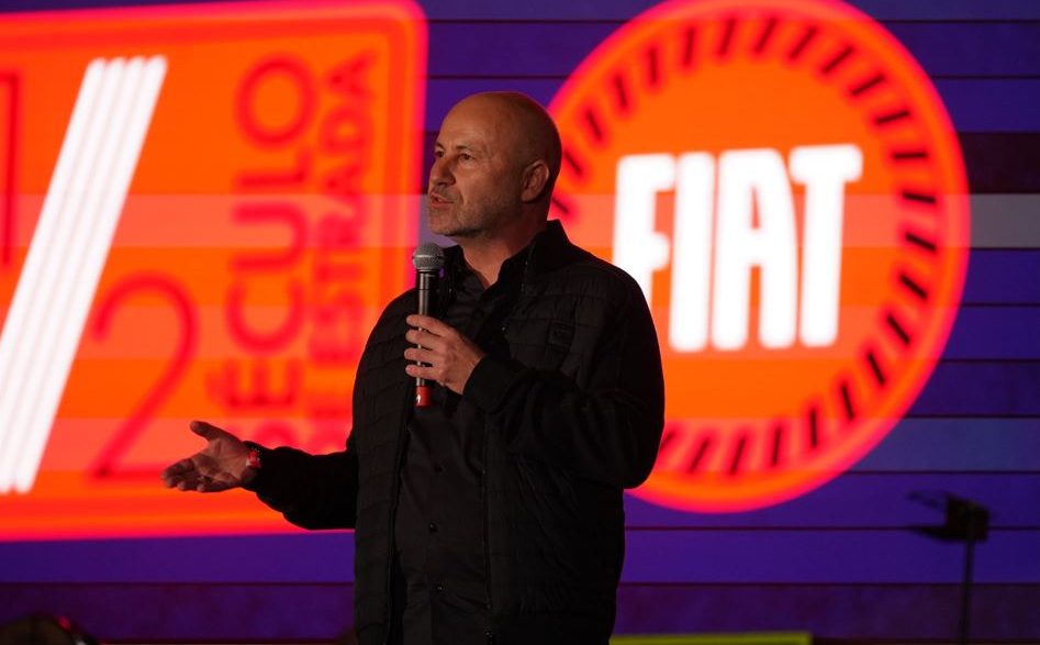 Herlander Zola, presidente da Stellantis para a América do Sul, fala ao microfone diante de um painel da Fiat.