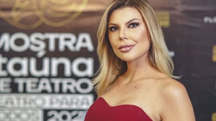 Mulher loira usando vestido vermelho posa em frente a painel de evento, com expressão confiante, representando matéria sobre comunicação e oratória em Belo Horizonte.