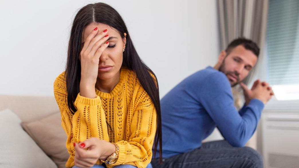 Casal discutindo a relação – casal sentados em uma cama tristes.