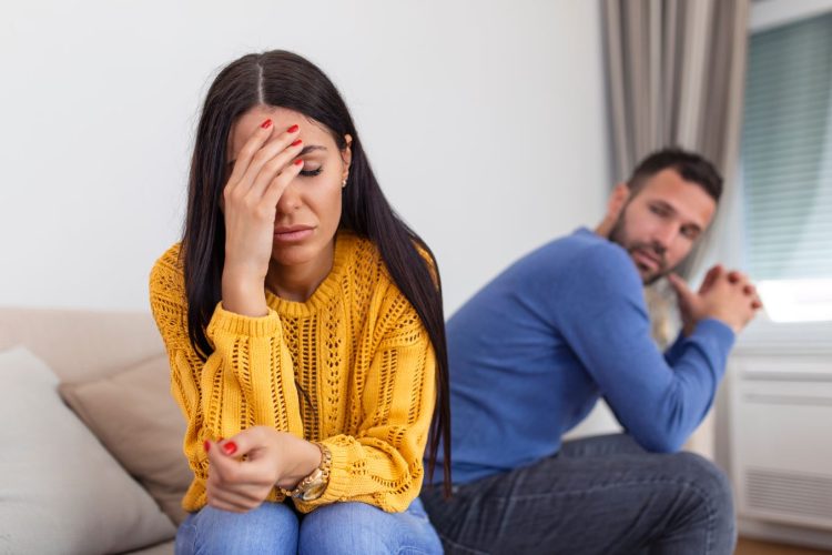 Casal discutindo a relação – casal sentados em uma cama tristes.