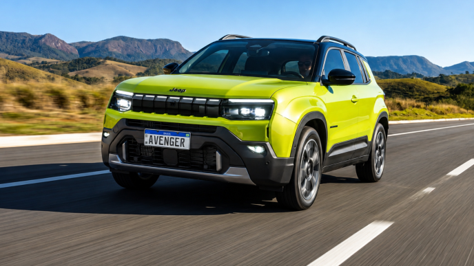 Jeep Avenger verde em movimento por uma rodovia, com montanhas ao fundo, destacando a grade de sete fendas, faróis em LED e rodas de liga leve.