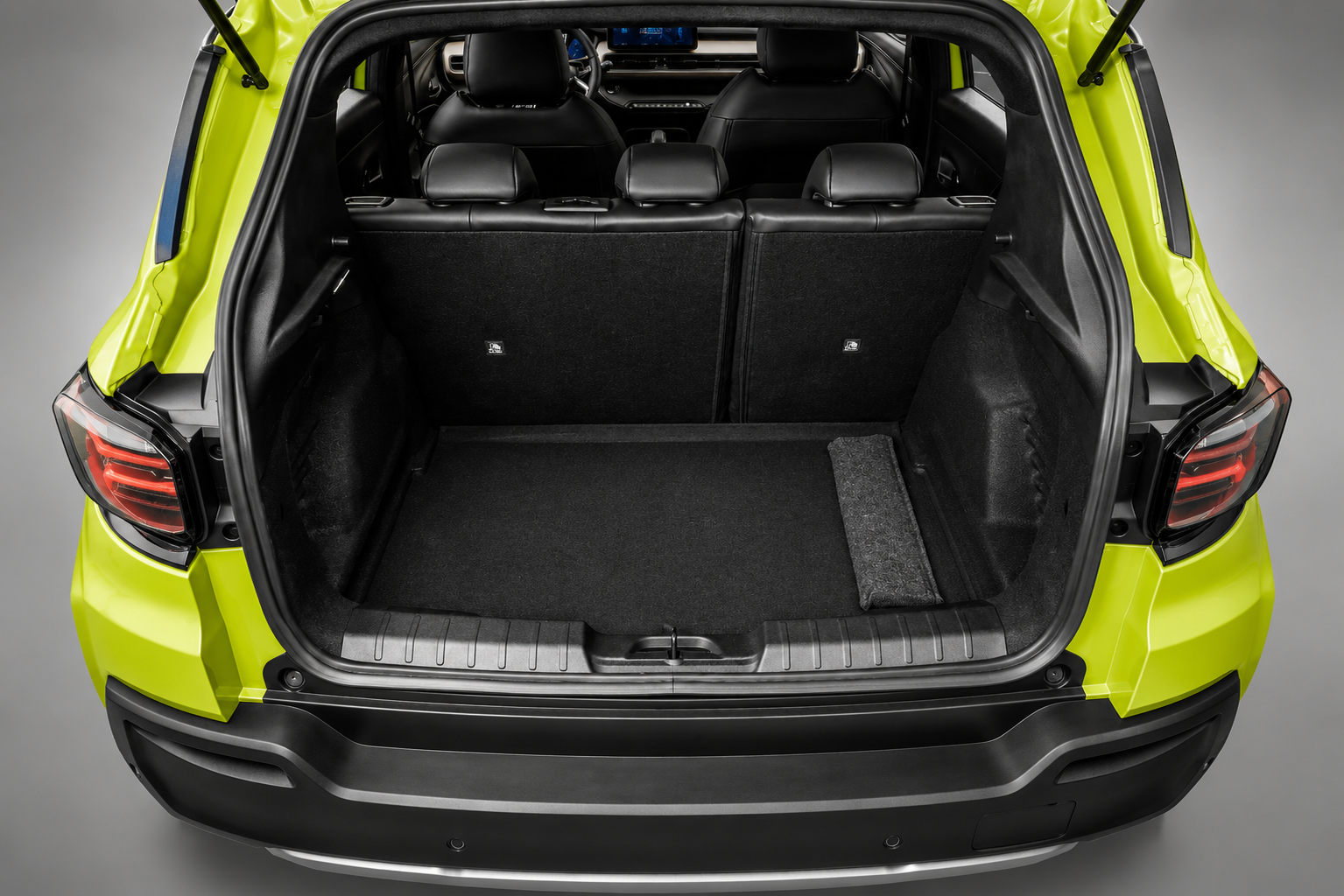 Porta-malas aberto do Jeep Avenger verde, com compartimento de carga amplo, bancos traseiros bipartidos e acabamento interno em preto.
