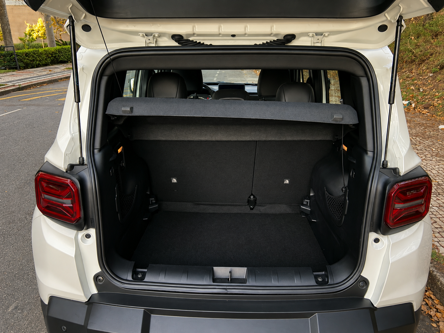 Porta-malas aberto do Jeep Renegade Sahara MHEV, com compartimento de bagagem revestido, cobertura superior e bancos traseiros visíveis.