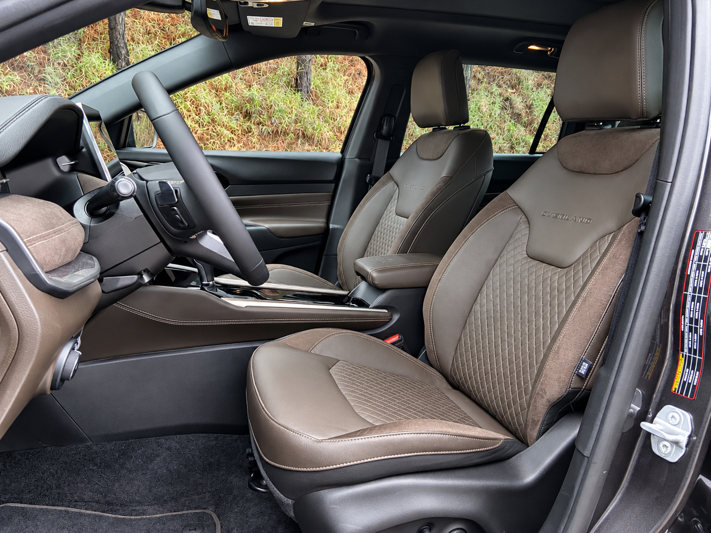 Interior do Jeep Commander Overland 2027 com bancos dianteiros revestidos em material premium, acabamento marrom e console central elevado.