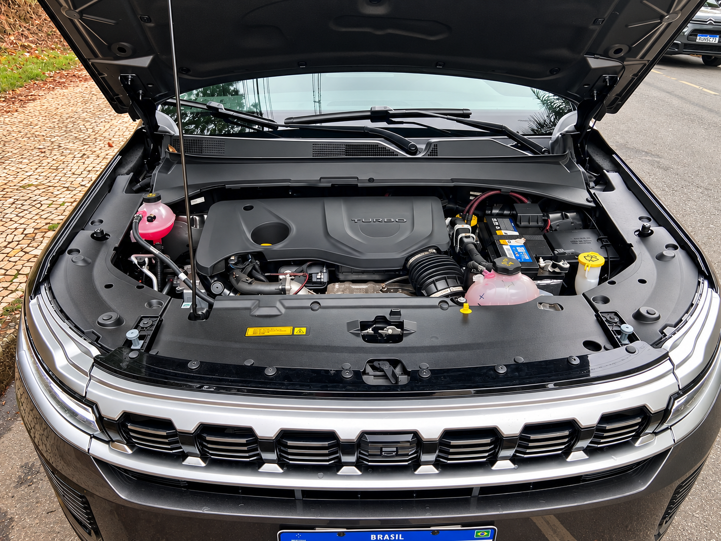 Compartimento do motor do Jeep Commander 2027 com propulsor turbo, bateria e reservatórios visíveis sob o capô aberto.