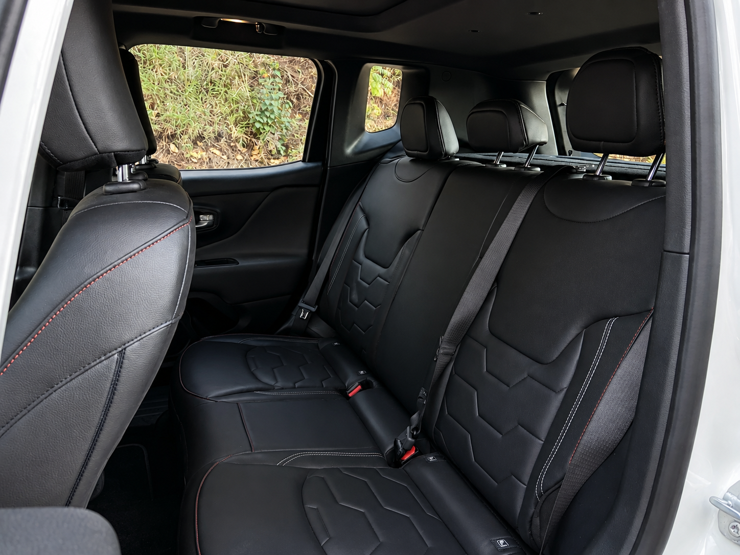Jeep Renegade Banco traseiro do Jeep Renegade Sahara MHEV, com três apoios de cabeça, revestimento escuro, costuras contrastantes e cintos de segurança de três pontos.
