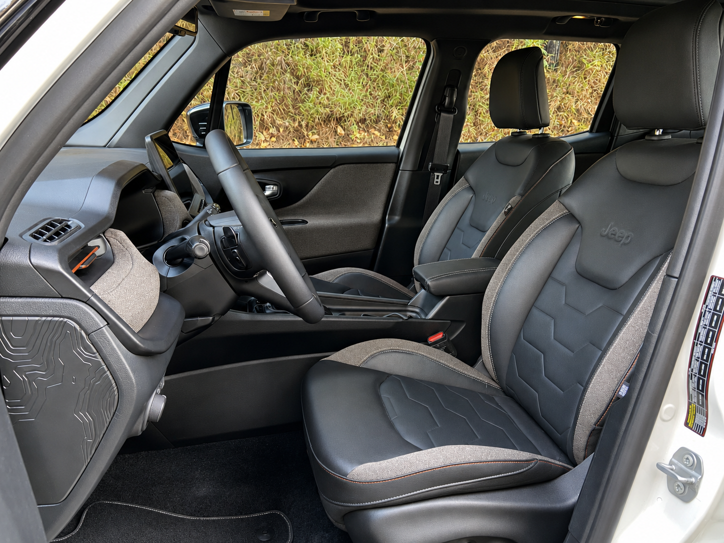 Bancos dianteiros do Jeep Renegade Sahara MHEV, com revestimento em tons escuros, detalhes contrastantes e acabamento sofisticado no interior.