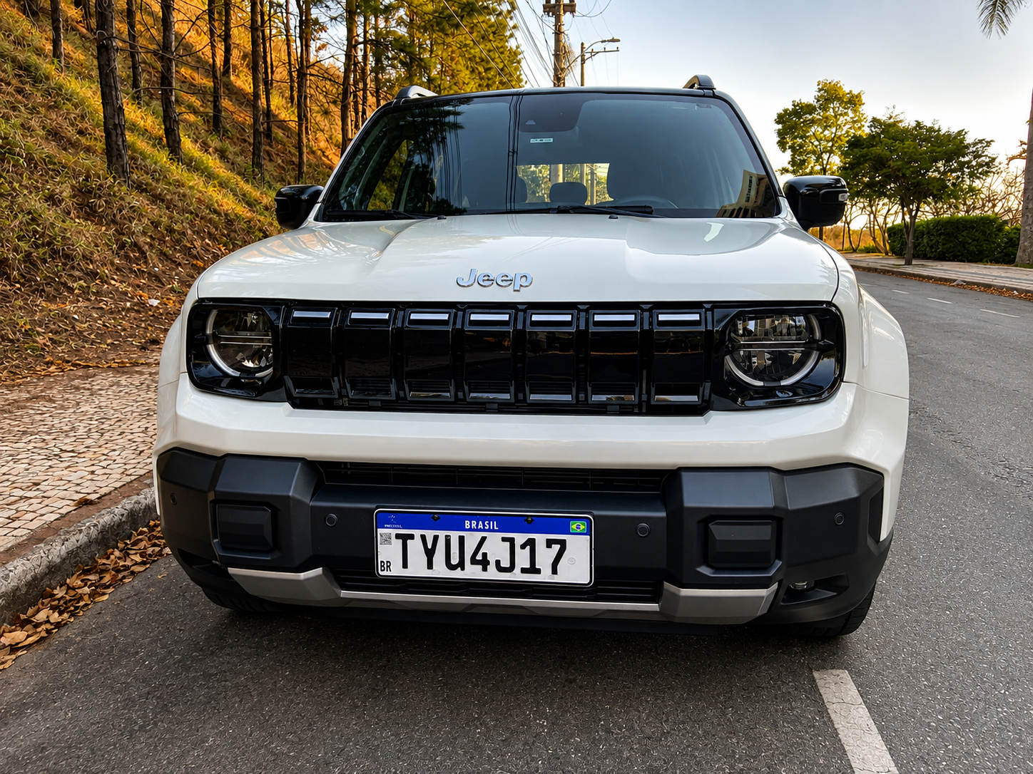 Dianteira do Jeep Renegade Sahara MHEV branco, com faróis redondos, grade preta de sete fendas e para-choque de desenho robusto.