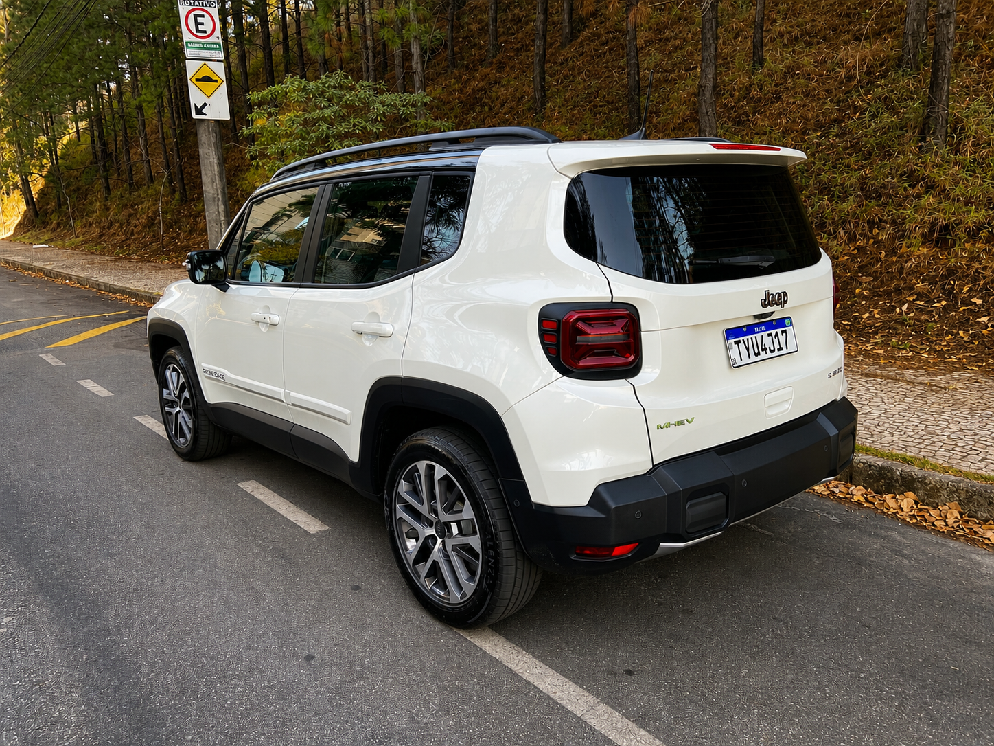 Traseira do Jeep Renegade Sahara MHEV branco, com lanternas de assinatura em “X”, identificação MHEV e para-choque robusto em acabamento preto.
