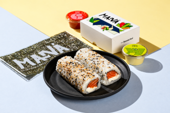 Hand rolls de salmão com cream cheese e gergelim em prato preto, acompanhados de nori e embalagens do Maná Hand Roll.
