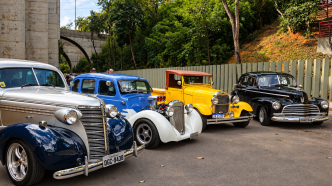 Carros antigos e hot rods coloridos reunidos em exposição automotiva, com modelos clássicos em destaque.