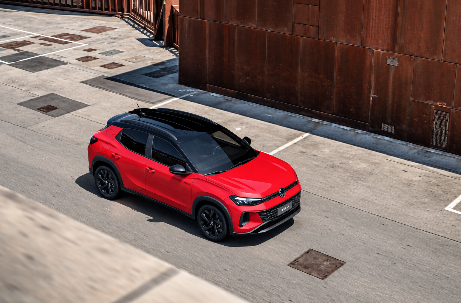 Volkswagen Tera 200 TSI vermelho visto de cima em ambiente urbano, com teto preto, rodas escurecidas e desenho frontal destacado.