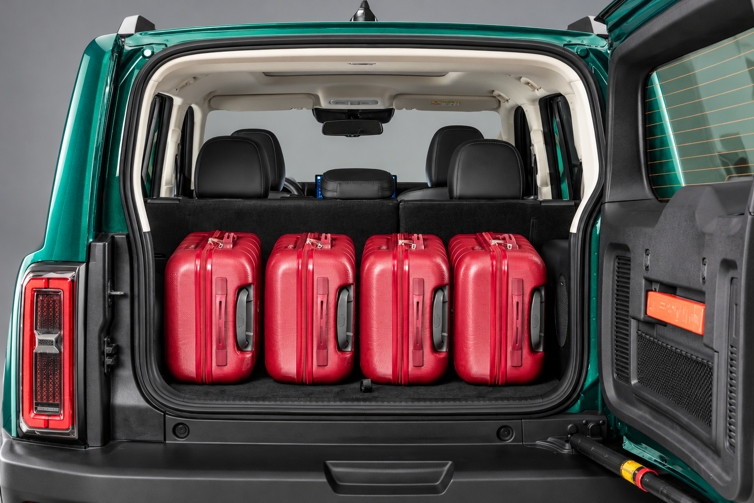 Porta-malas do GWM Haval H7 híbrido plug-in flex com capacidade de 586 litros, exibindo quatro malas vermelhas acomodadas no compartimento, bancos traseiros em posição normal e tampa lateral aberta.