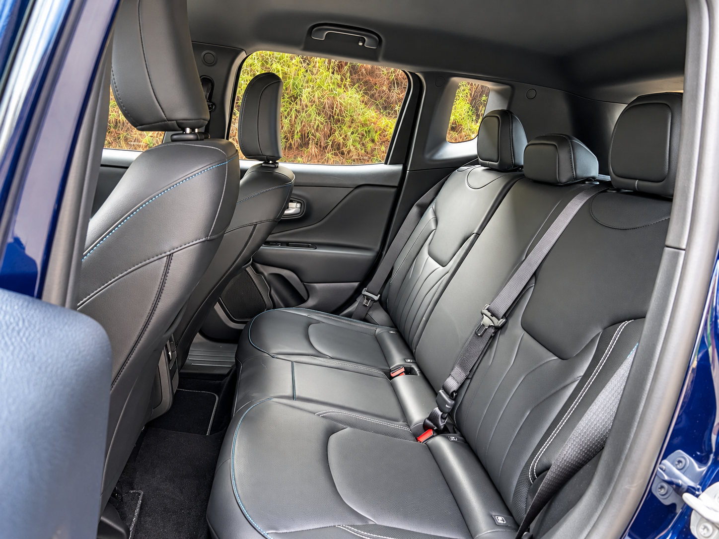 Interior traseiro do novo Jeep Renegade Longitude MHEV, com banco de três lugares, revestimento preto, costuras contrastantes, apoios de cabeça e cintos de segurança.