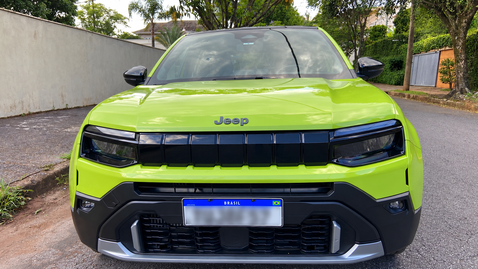 Jeep Avenger Longitude 2027 verde, fotografado de frente, destacando a tradicional grade de sete fendas em preto brilhante, faróis de LED e para-choque robusto com detalhes prateados.
