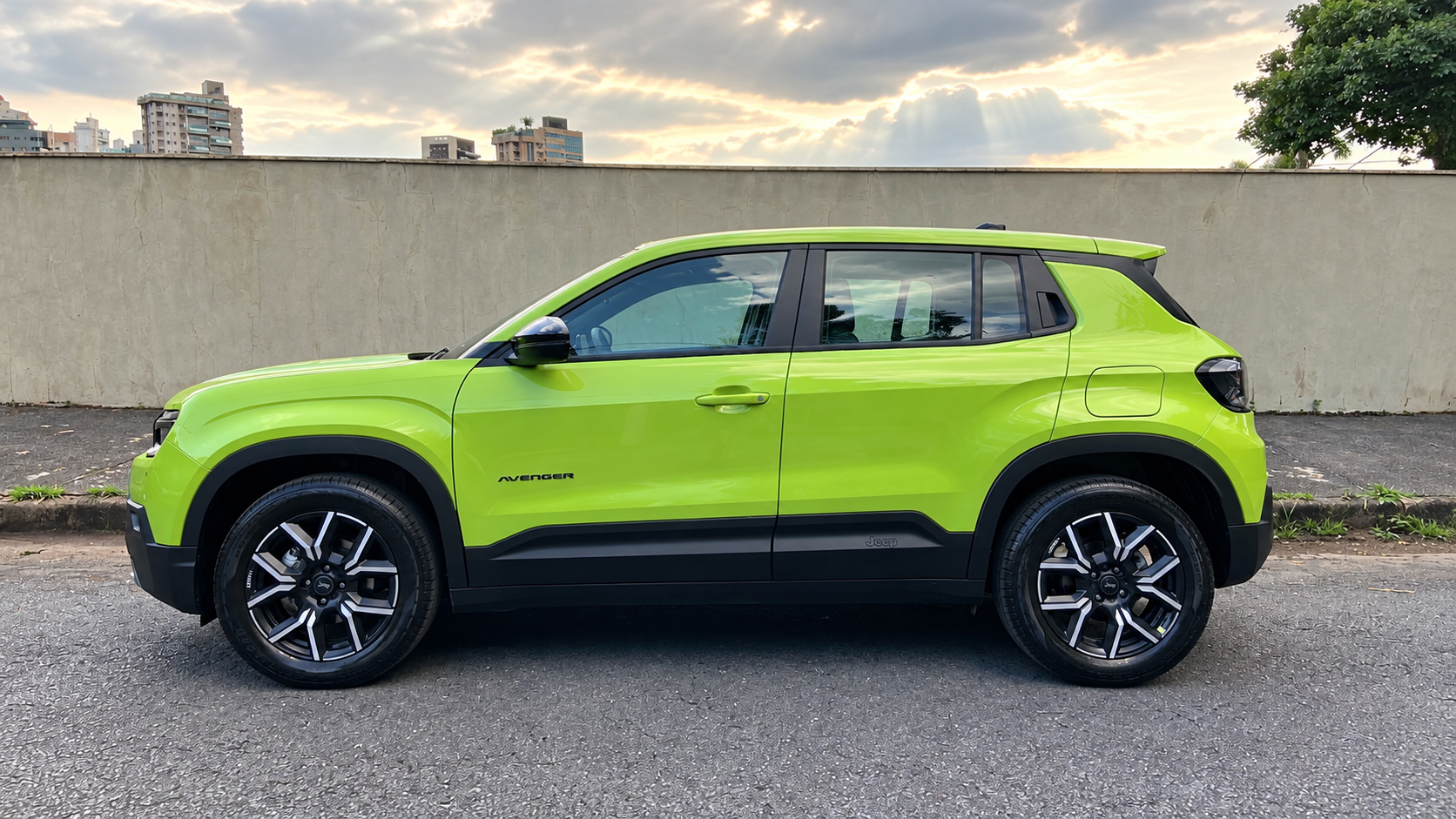 Jeep Avenger Longitude 2027 verde, fotografado de perfil, destacando as linhas laterais musculosas, rodas de liga leve de 17 polegadas, caixas de rodas trapezoidais e acabamento preto na carroceria.