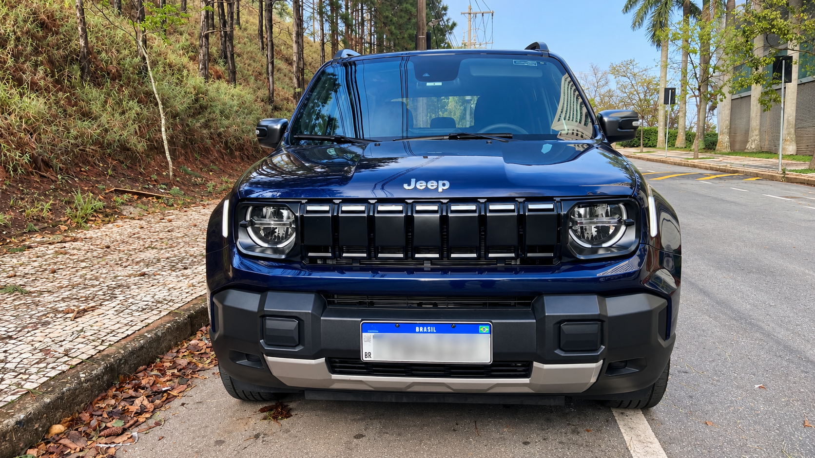 Vista frontal do novo Jeep Renegade Longitude MHEV azul, destacando a grade de sete fendas redesenhada, faróis circulares de LED e para-choque robusto.