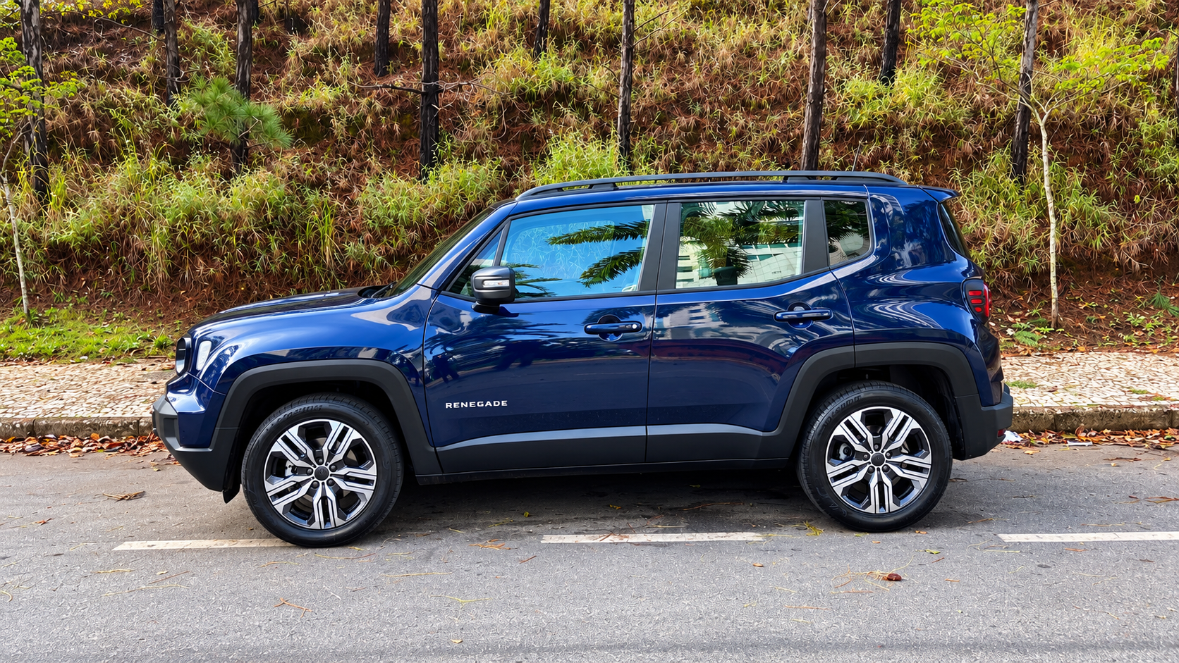 Novo Jeep Renegade Longitude MHEV azul visto de perfil, destacando rodas de liga leve de 18 polegadas, linhas robustas e design lateral renovado.