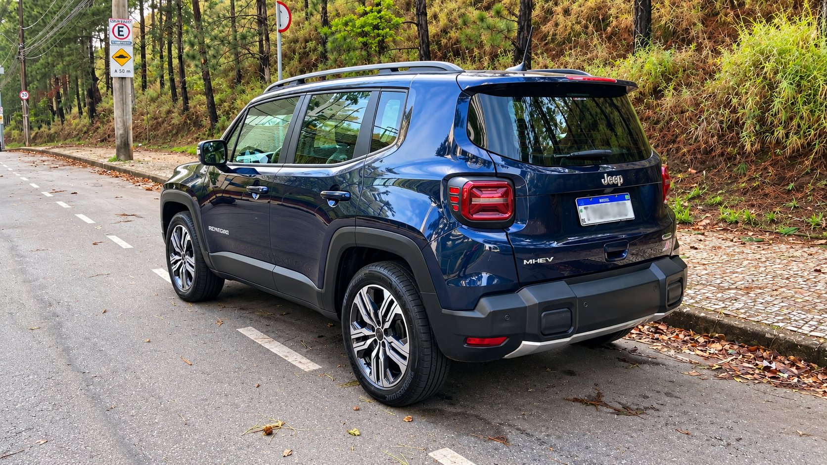 Vista traseira em três quartos do novo Jeep Renegade Longitude MHEV azul, destacando lanternas de LED em formato de X, emblema híbrido MHEV e para-choque robusto.