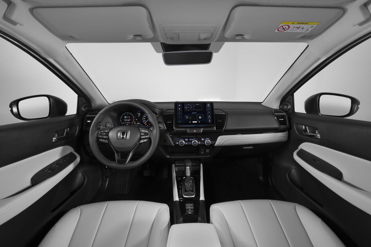 Interior do Honda City 2027 com painel moderno, central multimídia touchscreen, quadro de instrumentos digital, volante multifuncional, câmbio CVT e bancos claros.