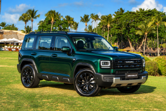 GWM Haval H7 híbrido plug-in flex na cor Verde Tijuca, visto de frente e lateral, com grade robusta, faróis de LED e rodas pretas, estacionado em resort tropical com palmeiras ao fundo.