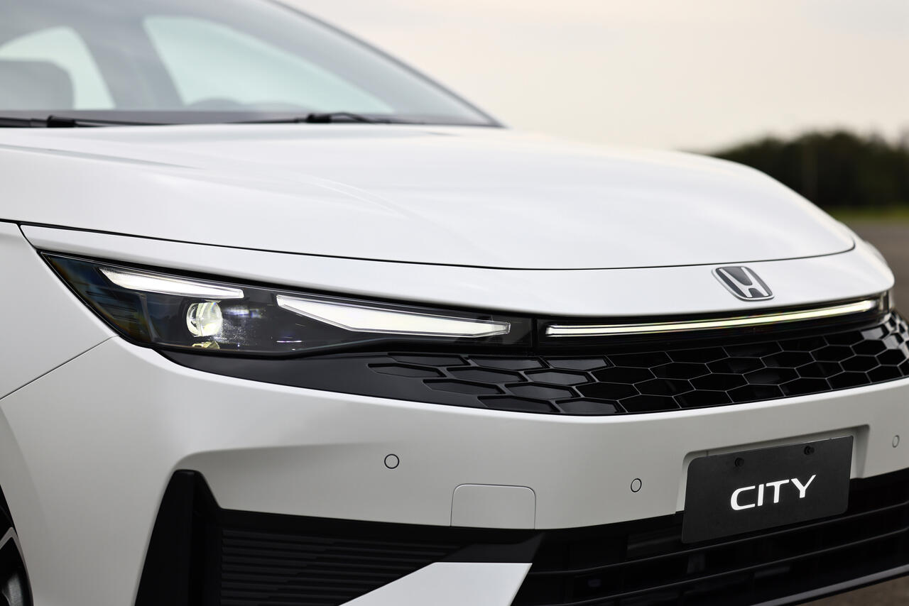 talhe da dianteira do Honda City 2027 branco, com novos faróis Full LED, luzes diurnas bipartidas, grade frontal em colmeia e logotipo Honda redesenhado.